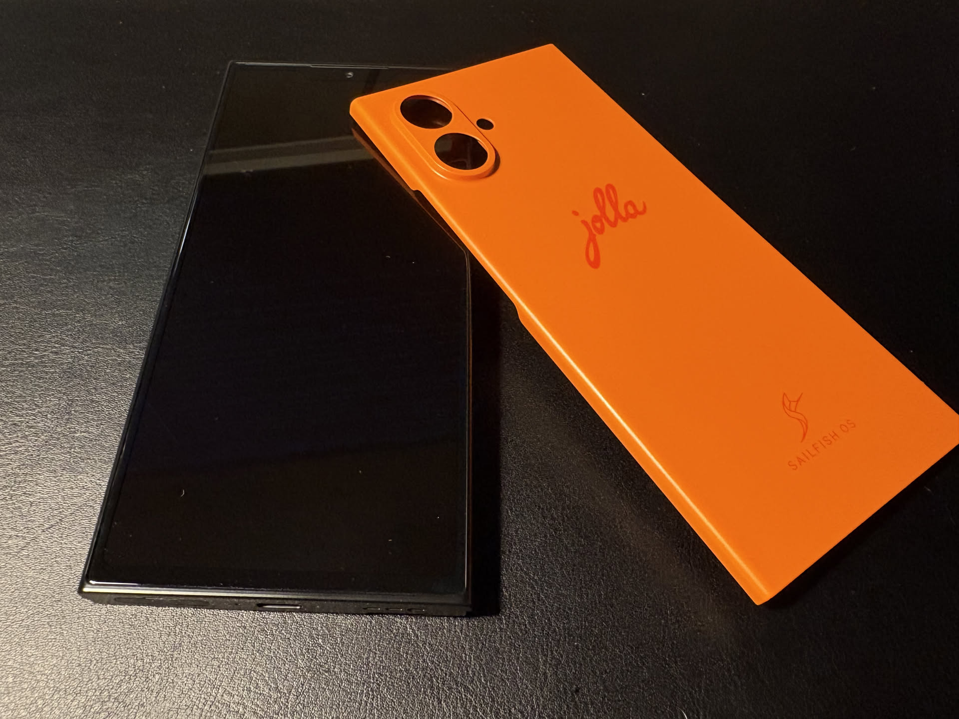 Jolla Phone - orange, laying on a black desk